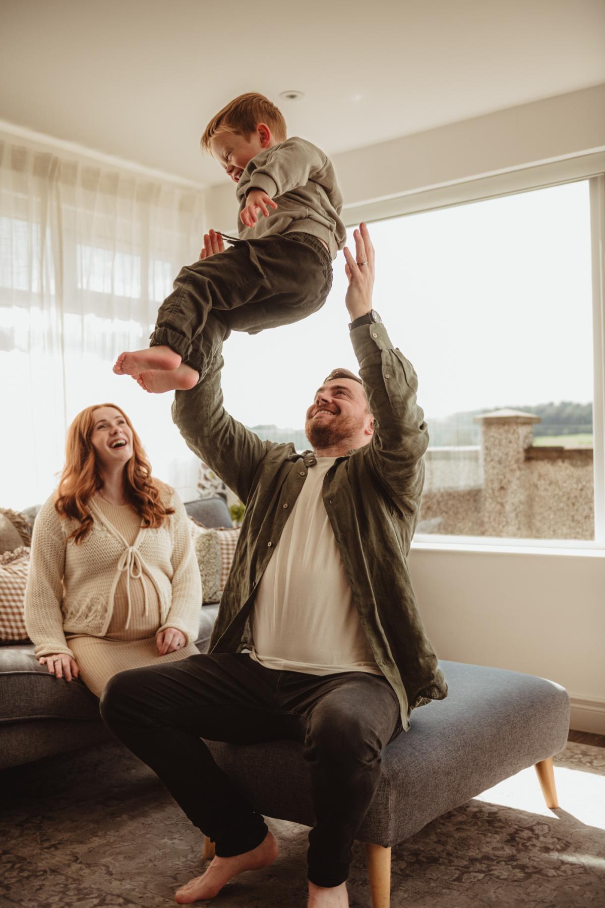 dad throwing child in air at home family photos