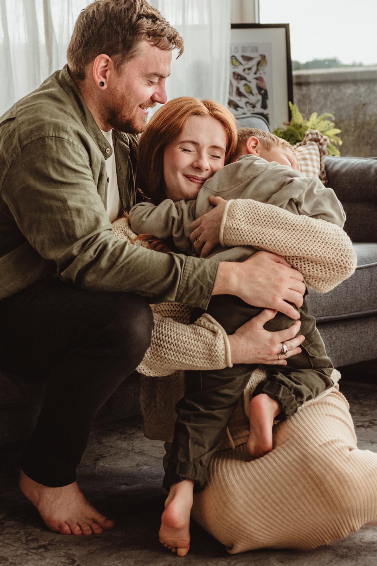 mum  and dad hugging toddler at home